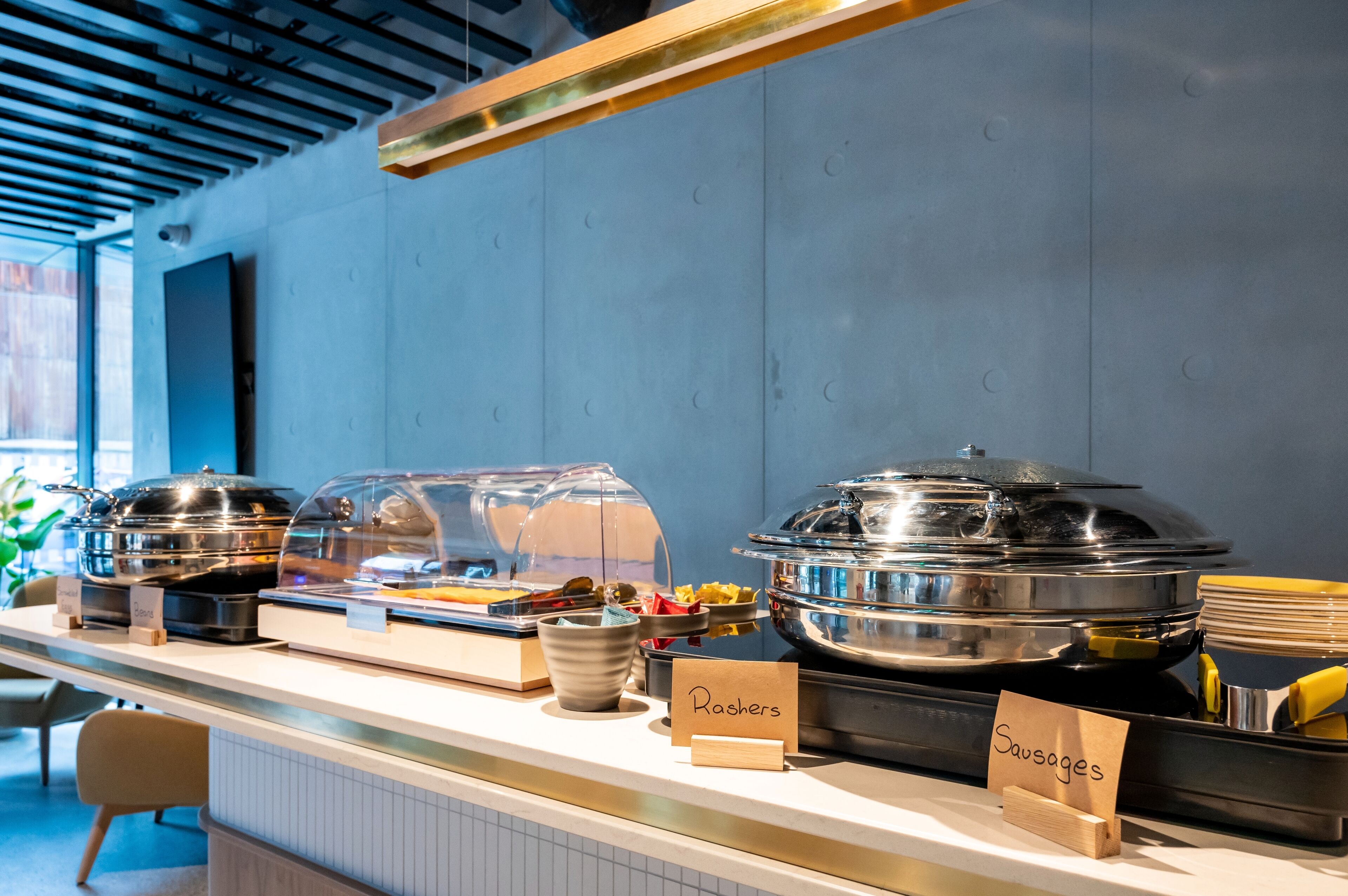 A buffet counter with labeled containers for Rishers and Sausages.