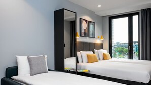 Een hotelkamer met twee bedden, een grote spiegel en uitzicht op de stad.
