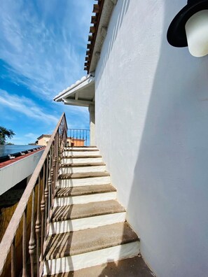 A staircase leading to a balcony with a railing, a white wall, and a clear blue sky. - Bilocale Tatiana Vista Mare (San Teodoro)