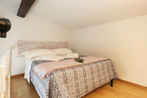A neatly made bed with a patterned bedspread, a decorative headboard, and a small plant on the bed.