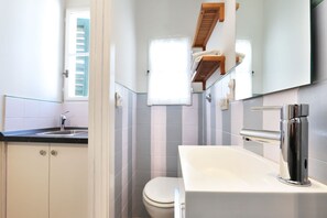 A modern bathroom with a white sink, a toilet, and a mirror above the sink.
