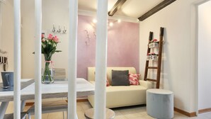 A room with a dining table, a sofa, a small stool, a vase with flowers, and a ladder against the wall. - Romantico Oltrarno - Sweet Dreams in Florence (Firenze)