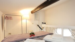A bedroom with a bed, a mirror, a towel rack, and a small stool. - Romantico Oltrarno - Sweet Dreams in Florence (Firenze)