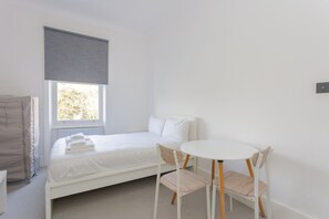 Une petite pièce propre, avec un lit simple, une table ronde et deux chaises.