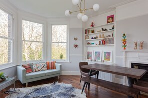 A cozy room with a light blue sofa, a wooden dining table, and a fireplace. - Newly Renovated 3 Bedroom Apartment in North West London (London)