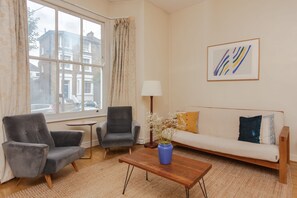 Un salon comprenant un canapé, deux fauteuils, une table basse et une lampe.