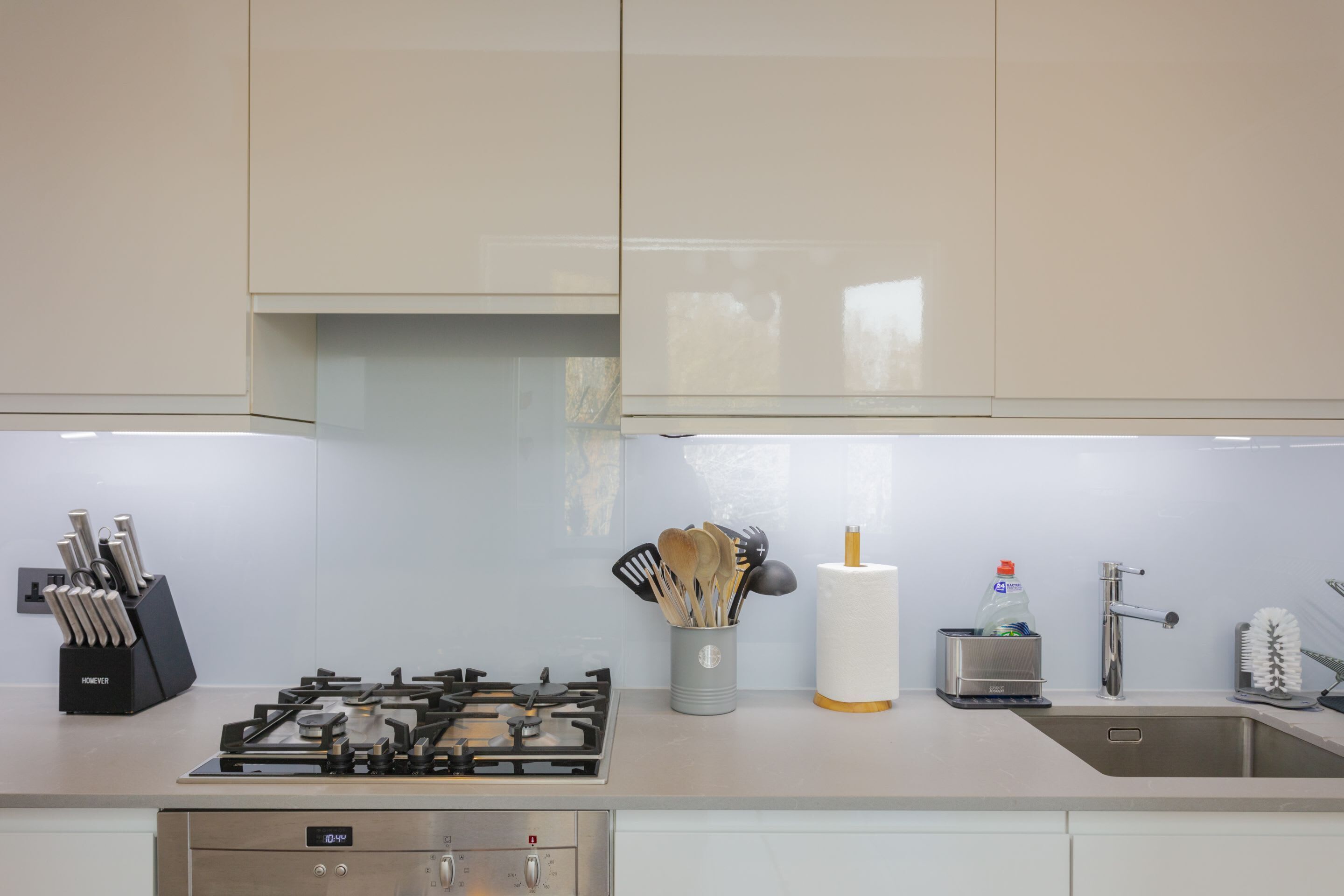 Une cuisine moderne équipée d’une cuisinière à gaz, d’un évier en acier inoxydable et d’un bloc à couteaux.