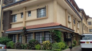 A multi-story building with a beige facade, large windows, and a red-tiled roof. - The Stand Leisure Nairobi West (Nairobi)