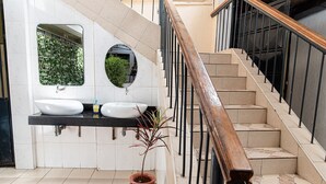 A modern bathroom with two sinks, a large mirror, and a staircase with a wooden handrail. - The Stand Leisure Nairobi West (Nairobi)
