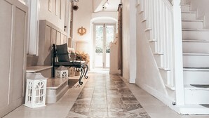 A spacious hallway with a patterned tile floor, a staircase with white railings, and a bench with a cushion. - La Luna Otel Cunda (Ayvalik)