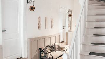A staircase with white railings and a patterned carpet leading to a landing with a bench and wall-mounted decor.