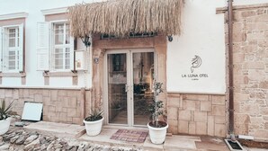 A building with a stone facade, a thatched roof entrance, and a sign reading "LA LUNA OTEL CUNDA". - La Luna Otel Cunda (Ayvalik)