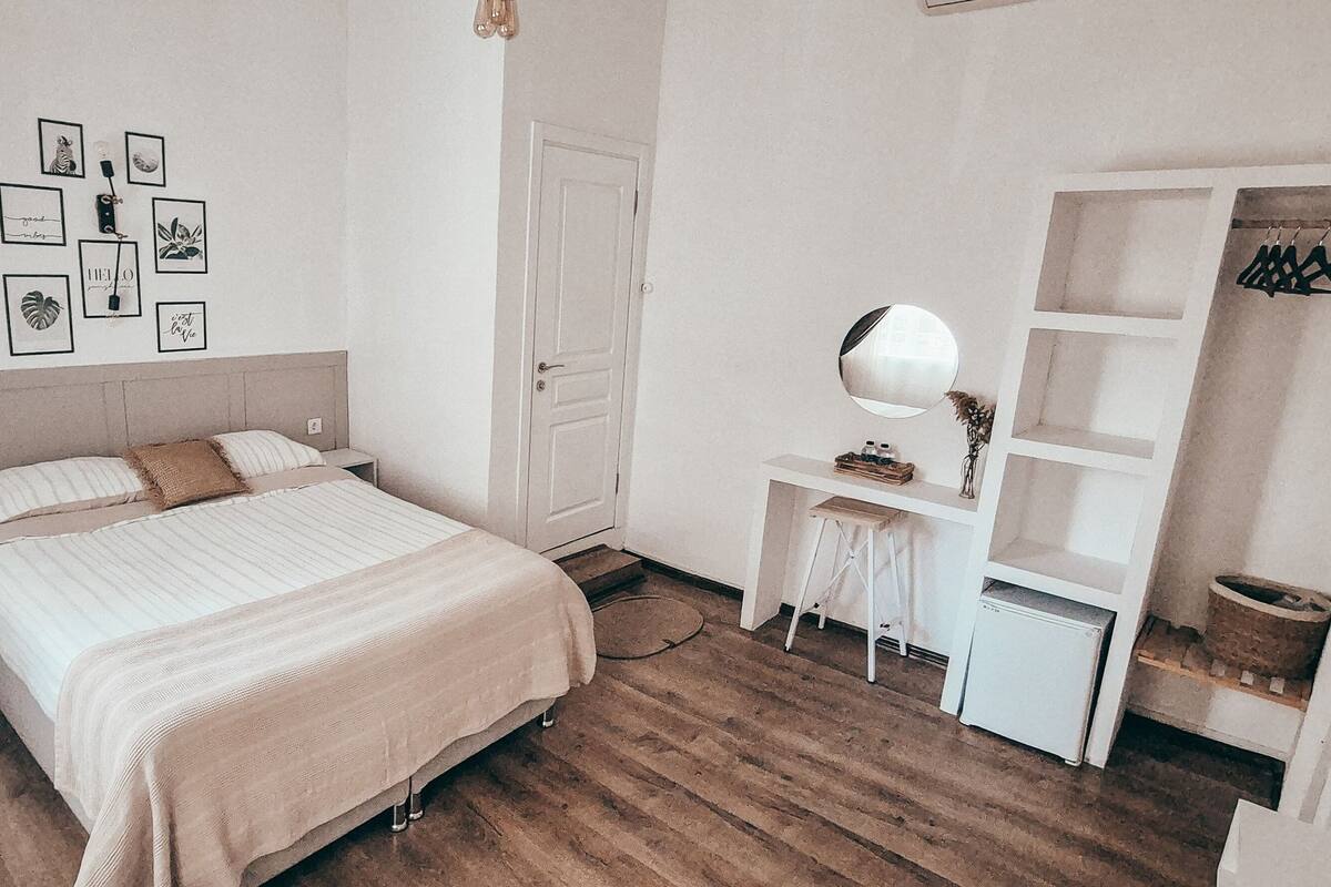 A bedroom with a bed, bedside table, dresser, and a wardrobe.