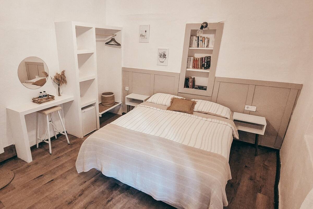 A bedroom with a bed, a desk, a wardrobe, and a bookshelf.