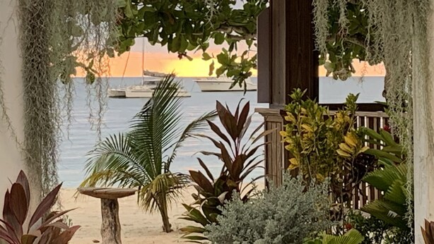 A beach view with a wooden gazebo, plants, and boats in the background. - Comfy Stay In Jamaica -enjoy 7 Miles Of White Sand Beach! 2 Bedroom Villa by RedAwning (Negril)