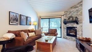 A cozy living room with a fireplace, a sofa, a coffee table, and a dog. - St. Anton 54 Steps to Canyon Lodge, Remodeled, Covered Parking by RedAwning (Mammoth Lakes)