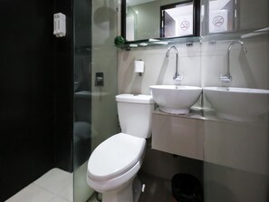 Ein modernes Badezimmer mit Toilette, zwei Waschbecken und einer Duschkabine aus Glas.
