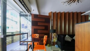 Ein modernes Interieur mit einem Essbereich, der orangefarbene Stühle, einen dunkelholztischen Tisch und ein schwarzes Sofa umfasst.
