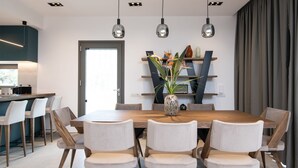 Un comedor moderno con una mesa de madera, sillas blancas tapizadas e iluminación colgante.