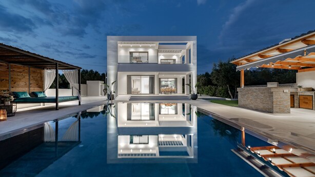 Una casa moderna de dos pisos con una piscina al frente.