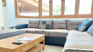 A cozy living room with a sectional sofa, a wooden coffee table, and a view through large windows. - Remarkable 2-bed Villa in Protaras (Paralimni)