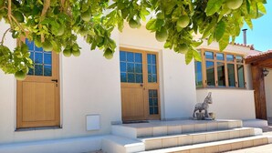A building with a white facade, wooden doors, and a stone statue on the steps. - Remarkable 2-bed Villa in Protaras (Paralimni)