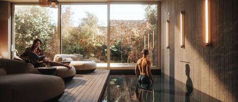 A modern spa area with a glass-enclosed hot tub, wooden flooring, and large windows offering a view of the outdoors.
