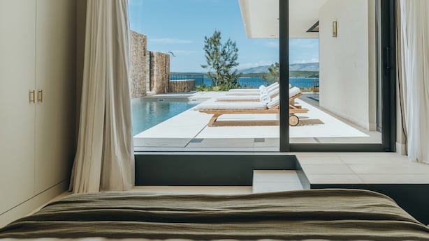 Un dormitorio con vistas a una piscina infinita y un paisaje montañoso.