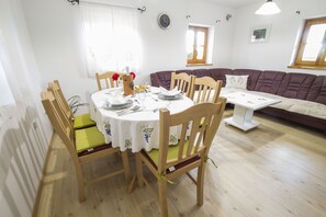 Ein Essbereich mit einem runden Tisch, Stühlen und einer Couch in einem hellen Raum mit Holzboden.