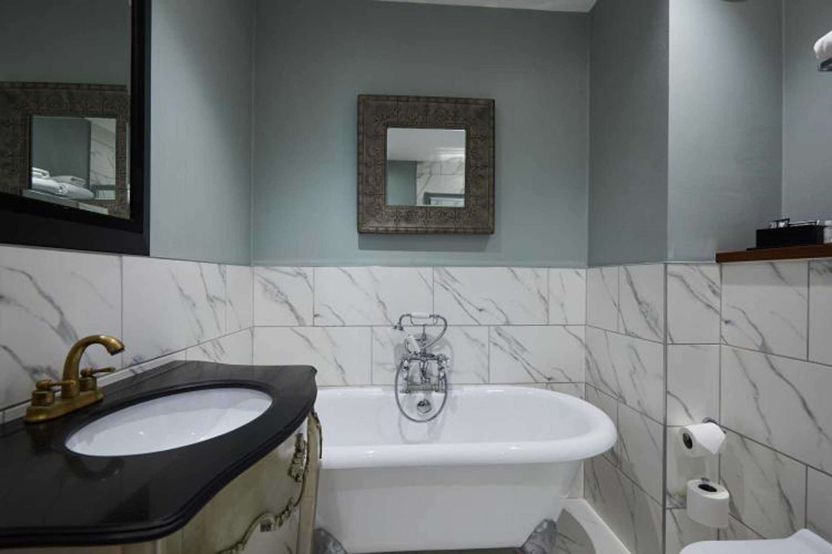 A bathroom with a black sink, a white bathtub, and a mirror on the wall.