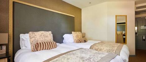 Habitación de hotel con dos camas, un espejo grande y un armario.