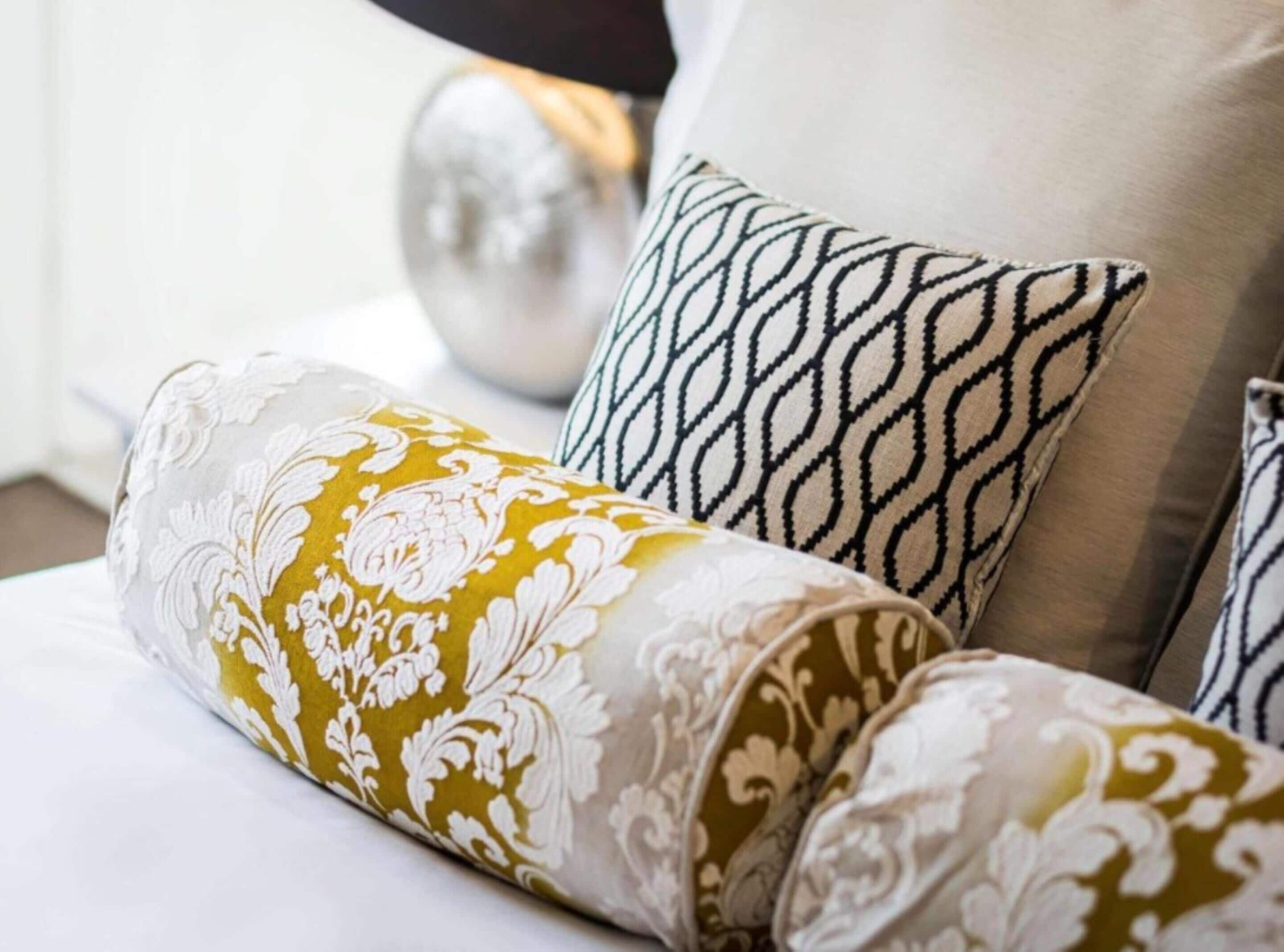 A bed with patterned pillows and a decorative pillow.