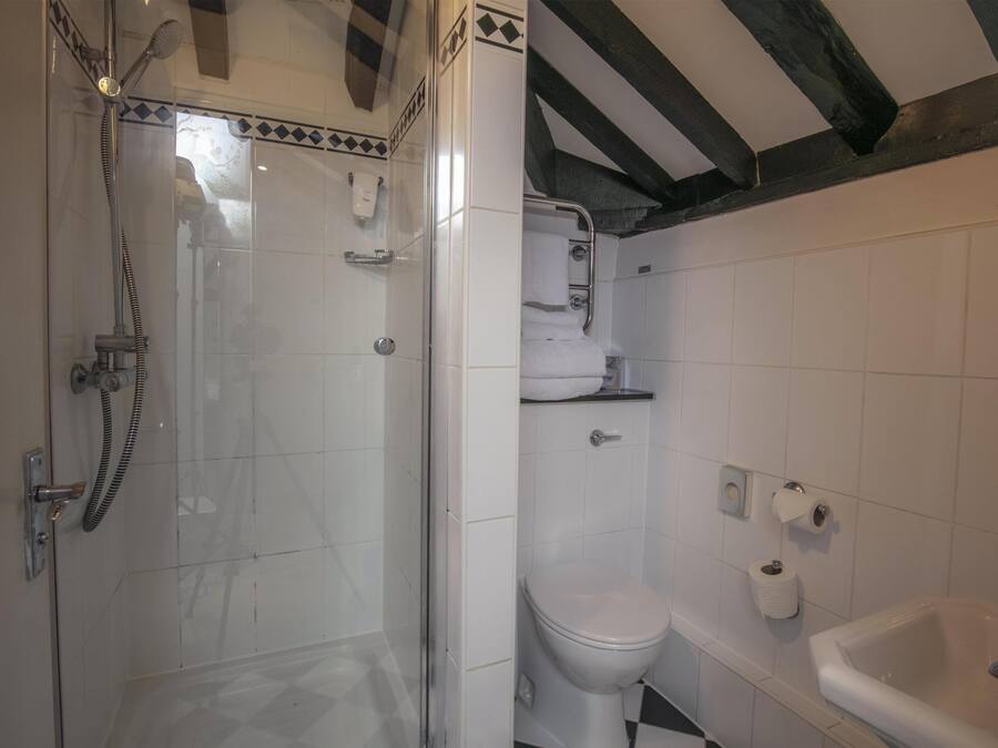 Un baño con ducha de vidrio, inodoro y lavamanos.