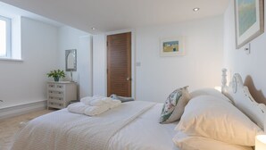 Ein Schlafzimmer mit einem großen Bett, einem Schminktisch, einer Tür und einem Fenster.