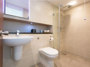 A modern bathroom with a glass-enclosed shower, a white sink, and a toilet. - Hepworth Apartment (St Ives)