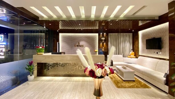 A modern hotel lobby with a reception desk, a sofa, and a TV mounted on the wall. - Springs Hotel (Tirupati)