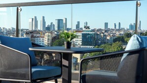 Een balkon met uitzicht over de stad, met moderne gebouwen en een heldere lucht.