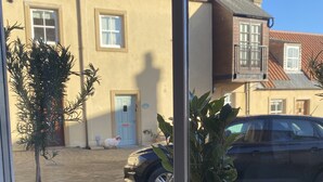 A window view of a building with a tiled roof, a parked car, and two potted plants. - Flemings Yard - Fantastic Town House in Anstruther (Anstruther)