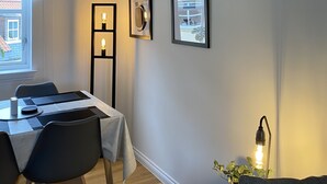 A dining area with a table set for two, two chairs, a potted plant, and framed artwork on the wall. - Flemings Yard - Fantastic Town House in Anstruther (Anstruther)