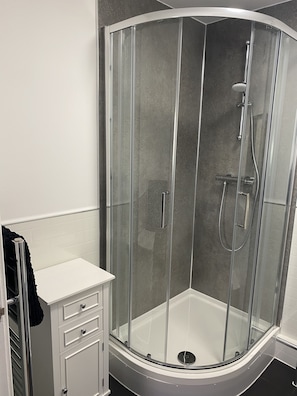 A modern bathroom with a glass-enclosed shower, a white vanity with drawers, and a black towel hanging on a rack. - Flemings Yard - Fantastic Town House in Anstruther (Anstruther)