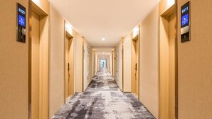 A long, narrow hotel corridor with a patterned carpet and wooden doors on either side. - Greentree Eastern Tianjin Dongli Development Zone Xinli Metro Station Hotel (Tianjin)