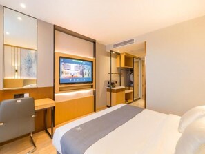 Una habitación de hotel moderna con cama, escritorio, televisor y armario.