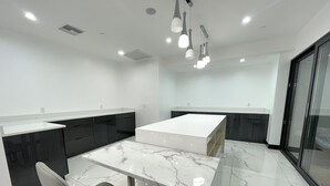 A modern kitchen with a marble countertop, dark cabinetry, and a glass door leading to a balcony. - Liberty View Brooklyn hotel (Brooklyn)