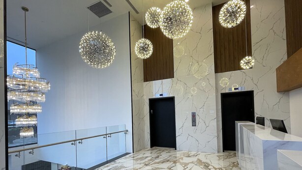 A modern lobby with marble flooring, a glass railing, and multiple chandeliers. - Liberty View Brooklyn hotel (Brooklyn)