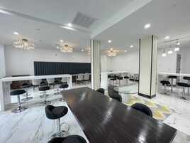 A modern conference room with a long table, multiple chairs, and a white reception desk.
