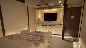 A modern hotel room with a large bed, a seating area, a flat-screen TV, and a minibar. - HOTEL Fuuga Luxury Resort - Adults Only (Maizuru)