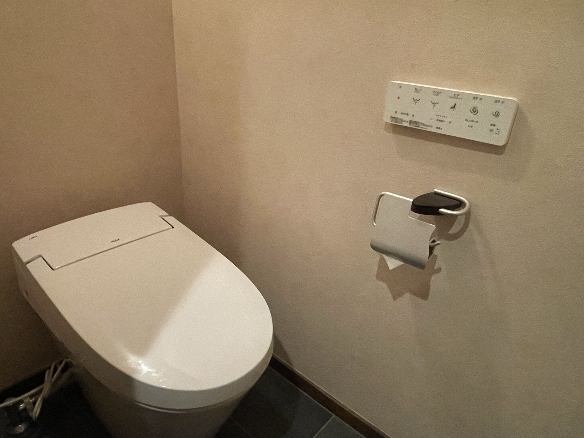 A white toilet with a flush handle and a wall-mounted flush button.