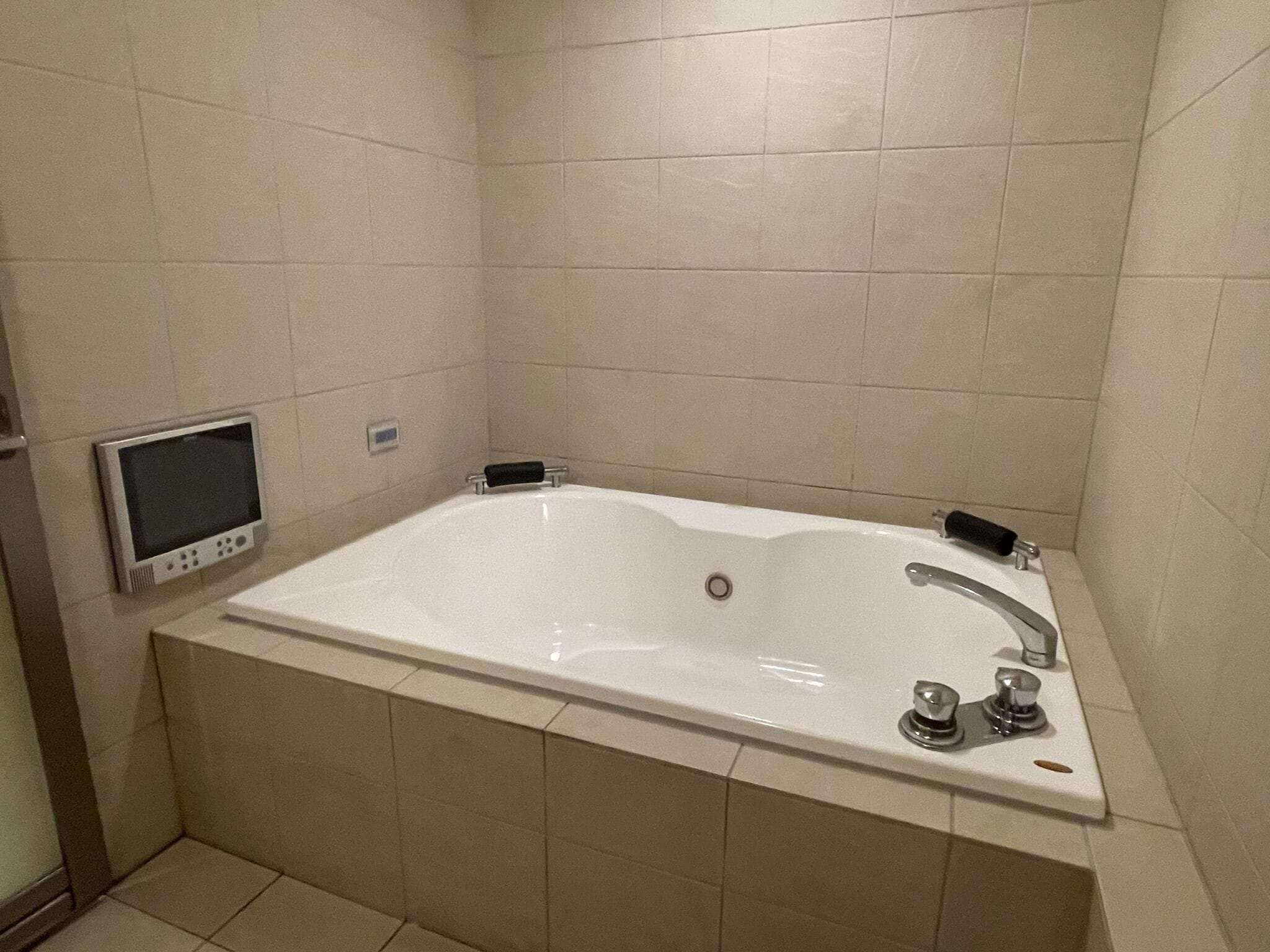 A modern bathroom with a large bathtub, a handheld showerhead, and a digital control panel.