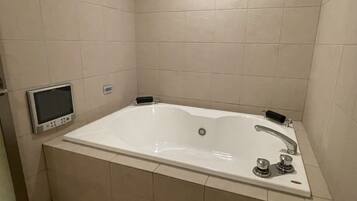 Un baño moderno con una bañera grande, un cabezal de ducha de mano y un panel de control digital.