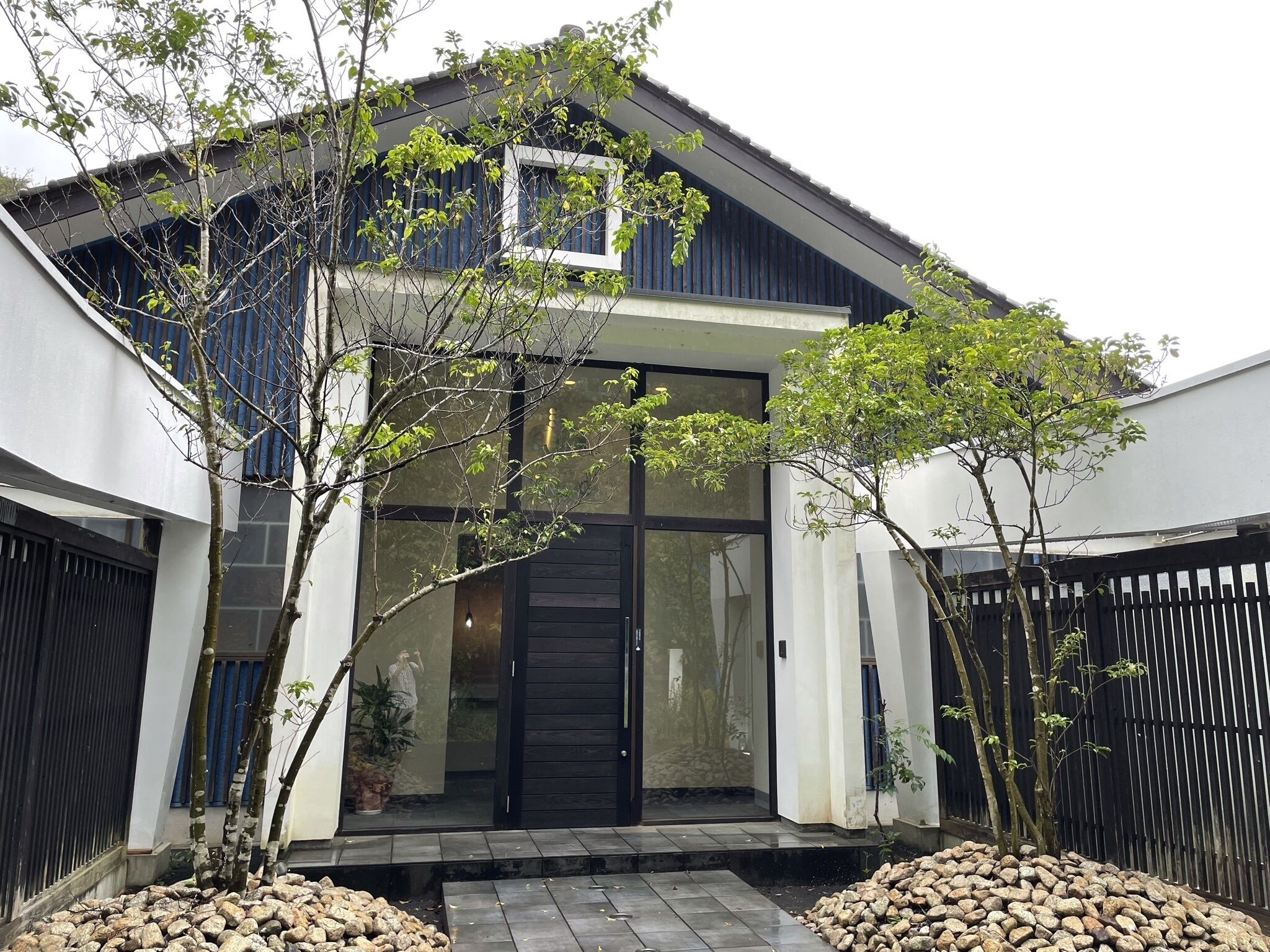 A modern house with a large glass door, a small porch, and a stone pathway leading to the entrance.